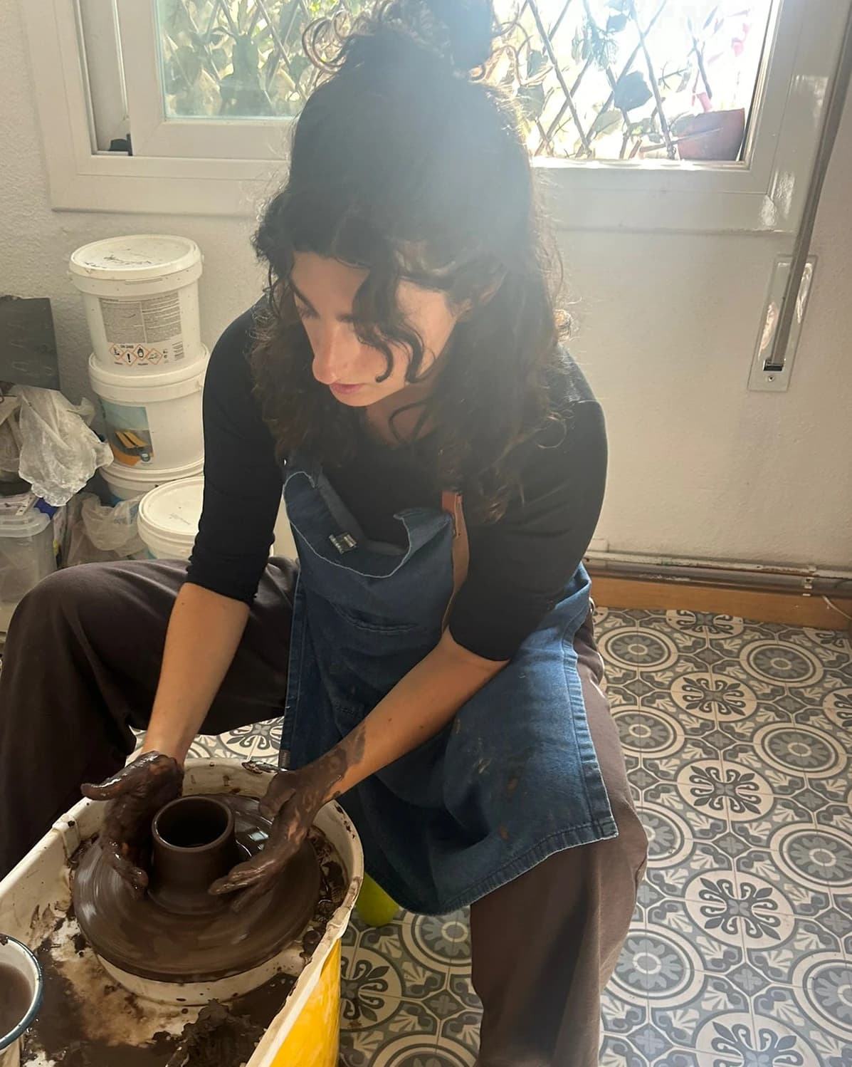Claudia shaping clay on a pottery wheel